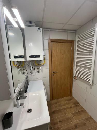 a bathroom with a sink and a mirror and a door at Lux apartment Rose in Kragujevac