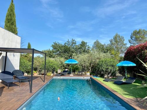 une piscine avec des chaises et des parasols dans l'arrière-cour dans l'établissement Villa ATHENA, à Lorgues