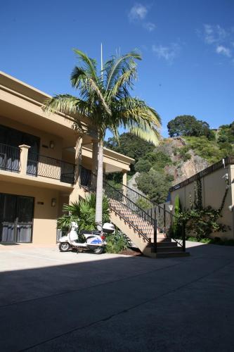a palm tree and a scooter parked in front of a building at Tuscany Villas Whakatane in Whakatane