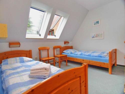 a bedroom with two beds and two chairs in it at Gaestehaus-Bruhn-5 in Alkersum