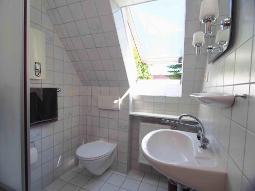 a bathroom with a sink and a toilet and a window at Gaestehaus-Bruhn-5 in Alkersum