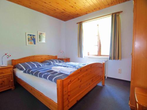 a bedroom with a wooden bed with a large window at Gaestehaus-Bruhn-1 in Alkersum