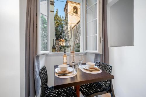 une table à manger avec des chaises et une fenêtre avec une tour dans l'établissement Charme & Authenticité au cœur de la vieille ville, à Saint-Laurent-du-Var