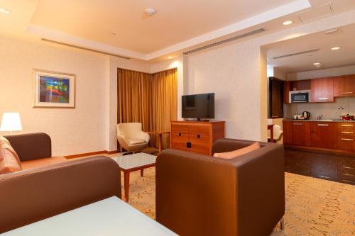a living room with a couch and a television at Holiday Inn - Suites Kuwait Salmiya by IHG in Kuwait
