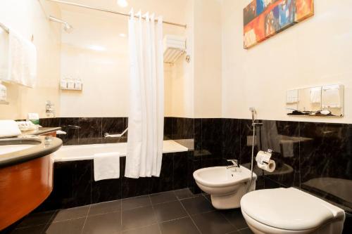 a bathroom with a toilet and a sink and a shower at Holiday Inn - Suites Kuwait Salmiya by IHG in Kuwait