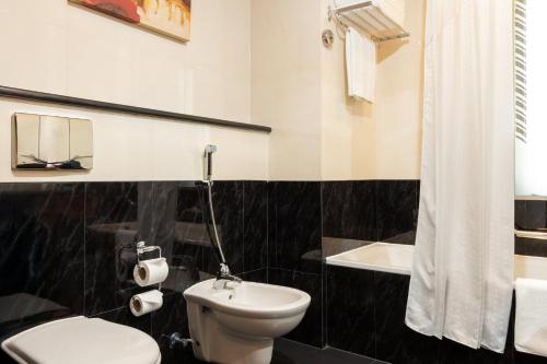 a black and white bathroom with a toilet and a sink at Holiday Inn - Suites Kuwait Salmiya by IHG in Kuwait