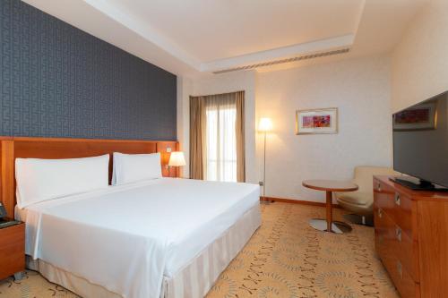 a bedroom with a large white bed and a television at Holiday Inn Kuwait by IHG in Kuwait
