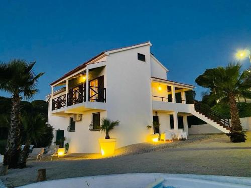 a large white house with palm trees in front of it at Casa Branca in Sesimbra