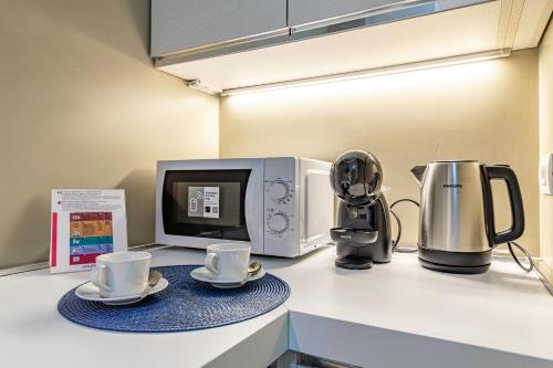 a kitchen counter with two cups and a microwave at Il quadrato blu in Vimercate