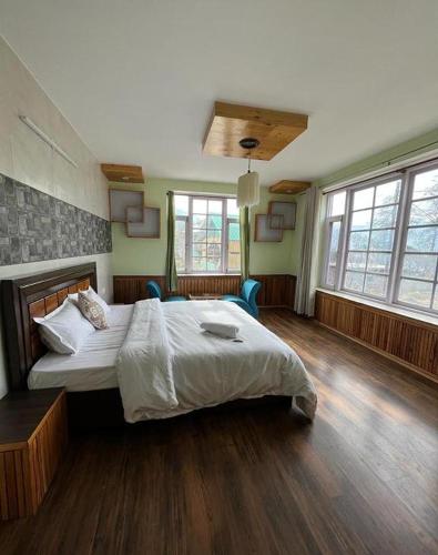 a large bedroom with a large bed and windows at Flüstern Manali in Nagar
