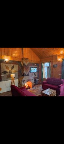 a living room with two purple couches and a fireplace at Cloud 9 wooden villa in Manāli