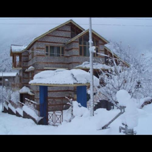 a log cabin with snow on the roof at Cloud 9 wooden villa in Manāli