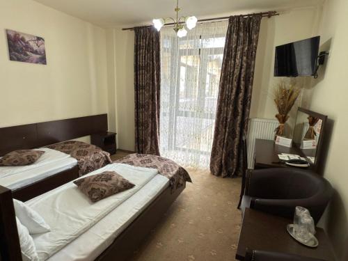 a bedroom with two beds and a chair and a window at Hotel Miky in Arad