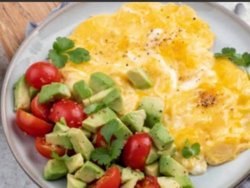 a plate of eggs and vegetables with tomatoes and avocado at Kausar guest house in Karabulak