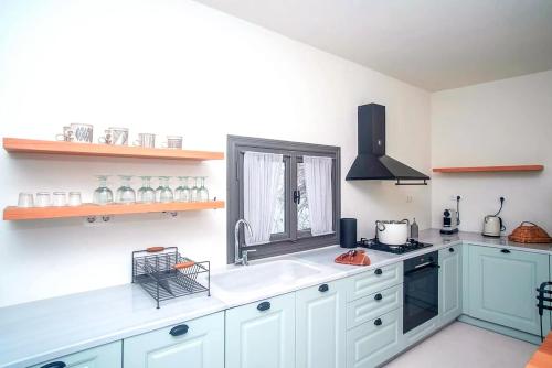 a kitchen with white cabinets and a sink and a window at Samos Serenity - Classic Retreat near the beach in Koumeika