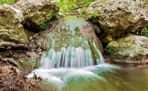 a waterfall in the middle of a river with rocks at Samos Serenity - Classic Retreat near the beach in Koumeika