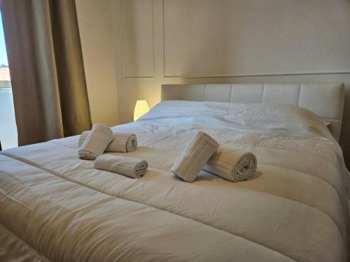 a white bed with three rolled towels on it at Be Your Home - Stazione Mare in Civitavecchia