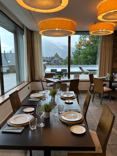 a dining room with a table and chairs and windows at Aparthotel Siente Boí & SPA in Pla de l'Ermita