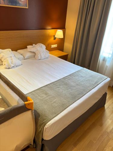 a hotel room with a bed with white sheets at Aparthotel Siente Boí & SPA in Pla de l'Ermita