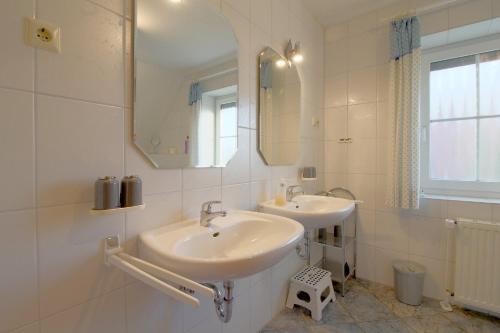 a white bathroom with two sinks and a mirror at MU17 Haus Godewind in Dorum Neufeld
