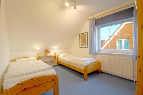 two beds in a room with a window at MU17 Haus Godewind in Dorum Neufeld