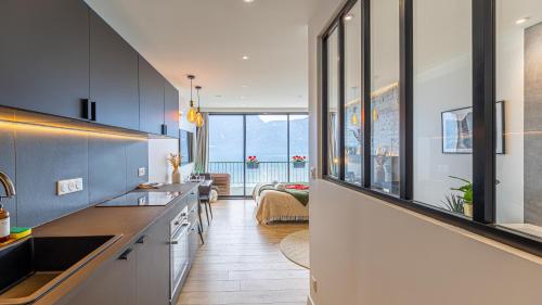 une cuisine avec des armoires en noir et blanc et un salon dans l'établissement L'Edelweiss du Lac, à Tresserves