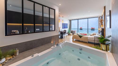 a large bath tub in a room with a bedroom at L'Edelweiss du Lac in Tresserves