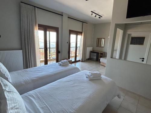 two beds in a hotel room with a mirror at Mamali Guesthouse in Verdikoússa