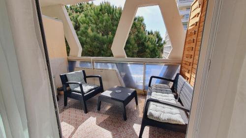 - un balcon avec 2 chaises, une table et 2 fenêtres dans l'établissement Suite Voile Clim Wifi Terrasse Plages 2min - ROSSIconciergerie - Linge inclus, à La Grande Motte