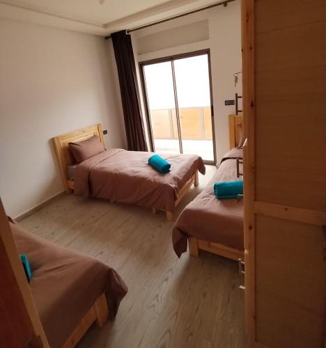 a room with three beds and a window at Nomad Surf Lodge in Imsouane