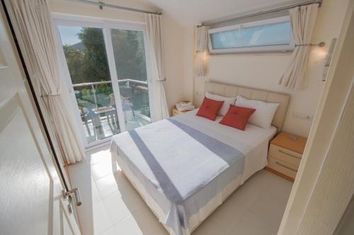 a bedroom with a bed with red pillows and a window at Sunset Apartments with pool in Kalkan in Kalkan
