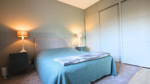 a bedroom with a bed with a blue blanket and two lamps at Villa avec Vue Panoramique et Piscine in Dieulefit