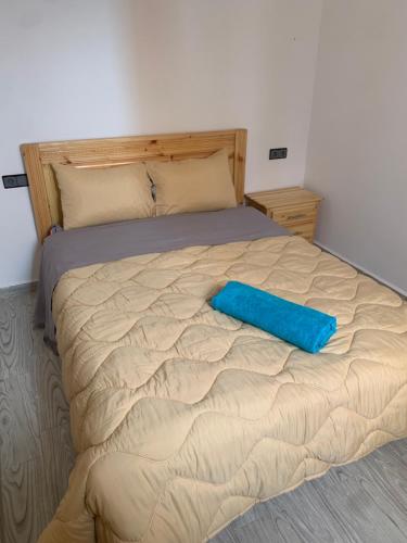 a bed with a blue pillow on top of it at Nomad Surf Lodge in Imsouane