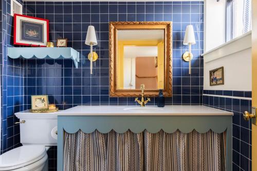 a blue tiled bathroom with a sink and a mirror at Luxe 1920 Schoolhouse Sleeps 8 30 Min From Okc in Guthrie