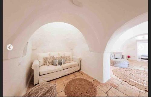 a living room with a white couch and an archway at Modern trulli with a beautiful new pool in Ceglie Messapica