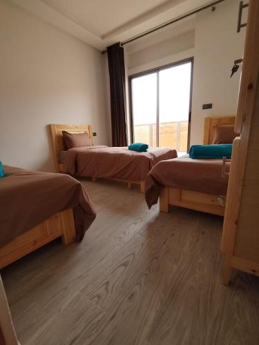 a room with three beds and a large window at Nomad Surf Lodge in Imsouane