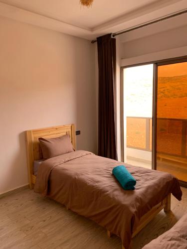 a bedroom with a bed with a large window at Nomad Surf Lodge in Imsouane
