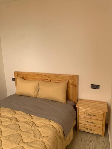 a bed with a wooden headboard and a night stand at Nomad Surf Lodge in Imsouane