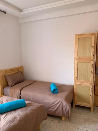 a bedroom with two beds and a dresser with a blue pillow at Nomad Surf Lodge in Imsouane