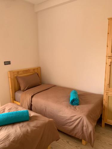 two beds in a small room with blue sheets at Nomad Surf Lodge in Imsouane