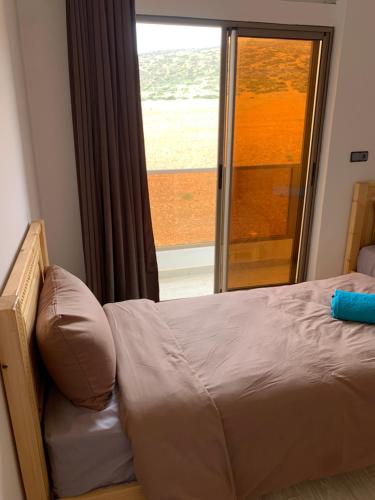a bed in a bedroom with a large window at Nomad Surf Lodge in Imsouane