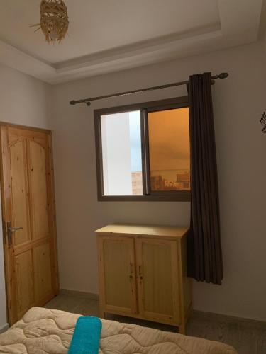 a bedroom with a window and a bed and a wooden cabinet at Nomad Surf Lodge in Imsouane