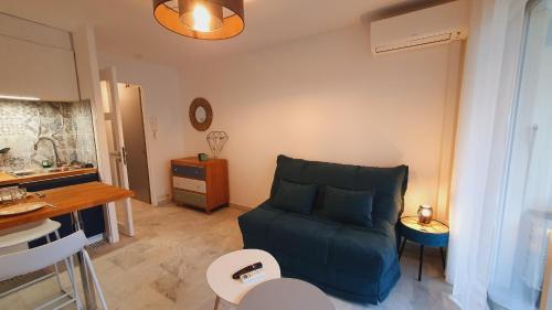 un salon avec un canapé bleu et une table dans l'établissement Suite Voile Clim Wifi Terrasse Plages 2min - ROSSIconciergerie - Linge inclus, à La Grande Motte