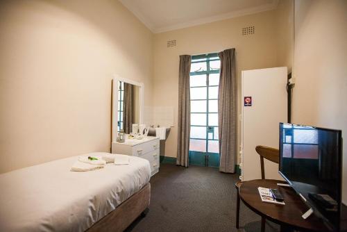 a hotel room with a bed and a television at Captain Stirling Hotel in Perth