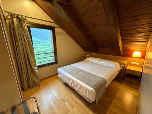 a bedroom with a bed and a large window at Aparthotel Siente Boí & SPA in Pla de l'Ermita