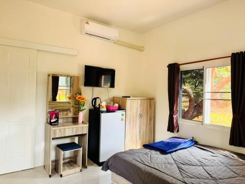 a bedroom with a refrigerator and a table and a window at ตาแอกะยายแดงโฮมสเตย์ in Ban Hong Khu