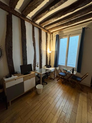 - un bureau avec un bureau et un ordinateur dans une pièce dotée de fenêtres dans l'établissement Studio cosy au cœur de Paris, à Paris