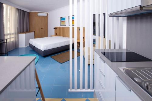 a room with a bed and a kitchen with blue tiles at Hotel Apartamento Foz Atlantida in Monte Gordo