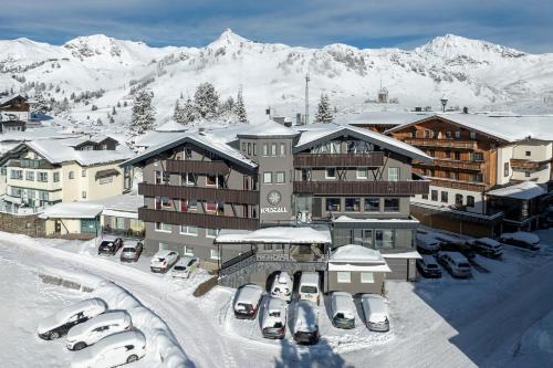 a large building with cars parked in the snow at Hotel Kristall in Obertauern