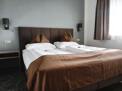 a large bed with white sheets and brown pillows at Ferienhotel Gewürzmühle in Radstadt